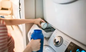 Dłoń wlewa płyn do prania do szufladki pralki. Właściwe miejsce, gdzie wlać płyn do prania, jest kluczowe dla czystych ubrań.