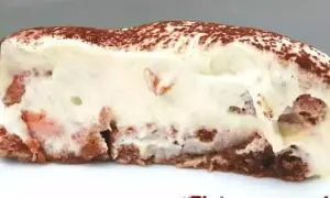 Tranche de tiramisu crémeux, parsemé de cacao, avec des morceaux de biscuit rose. Un délice !