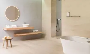 Baño moderno con lavabo flotante, bañera blanca y ducha. El suelo de madera clara contrasta con los azulejos de la pared.