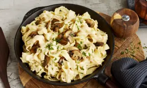 Cremiges Pasta Alfredo mit Pilzen, garniert mit Petersilie, serviert in einer Gusseisenpfanne.