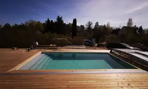 Arbetare bygger in pool med trädäck. Vattnet glittrar i solen. Snart redo för bad!