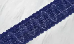 Elegancka, granatowa koronka z delikatnym wzorem, ułożona na białym tle.