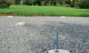 Gotowe fundamenty z betonu pod słupy wiaty, osadzone w żwirze.