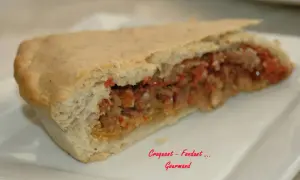 Une part d'impanata siciliana, une tourte sicilienne garnie d'une farce savoureuse, sur une assiette blanche.