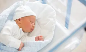 Śpiący noworodek w czepku z napisem "DADDY". To maleństwo zasługuje na becikowe, które pomoże rodzicom w pierwszych miesiącach życia.