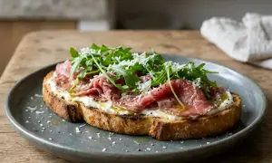 Tartine gourmande avec un accompagnement carpaccio de boeuf, roquette fraîche et copeaux de parmesan. Un délice pour les papilles.