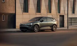Elegante Volvo EX60 verde metallizzato parcheggiata davanti a un edificio moderno con facciata geometrica.