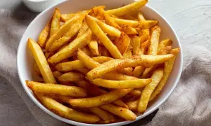 Chrupiące frytki z airfryer, posypane przyprawami, w białej misce. Idealna przekąska na szybki obiad.