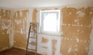 Renovierungsarbeiten: Eine Leiter steht bereit, um die Wände für das Rigips spachteln vorzubereiten. Das Zimmer wartet auf frischen Putz.