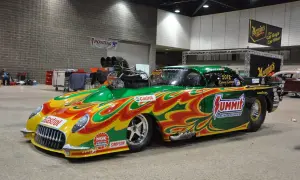 Une voiture de dragster aux couleurs vives, un exemple de tuning extrême, avec un moteur surdimensionné et des flammes peintes.