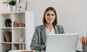 Kobieta w biurze przy laptopie, zastanawia się, czy liceum wlicza się do lat pracy.