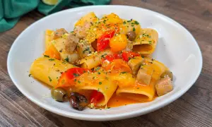 Paccheri con tonno fresco, pomodorini, olive e scorza di limone. Un piatto colorato e saporito, pronto per essere gustato.