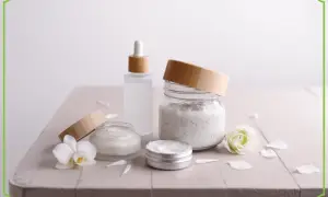 Kremy i serum w szklanych słoiczkach z bambusowymi nakrętkami, ozdobione kwiatami. Naturalne składniki, jak eugenol, dbają o skórę.