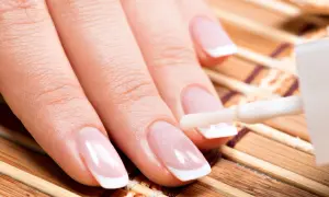 Dłoń z idealnym francuskim manicure, na paznokcie nakładana jest najlepsza odżywka do paznokci.