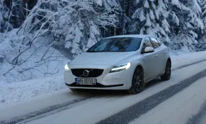 Białe Volvo V40 D3 pokonuje ośnieżoną drogę w lesie.