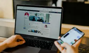 Osoba przegląda profil na Facebooku na laptopie, szukając informacji, jak usunąć znajomego na FB. Obok leży smartfon.