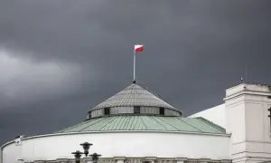 Polski parlament pod burzowym niebem. Biało-czerwona flaga powiewa na maszcie, symbolizując stan wyjątkowy w Polsce.