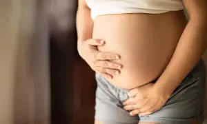 Brzuch ciężarnej kobiety, która zastanawia się, czy dziecko w brzuchu robi kupę.