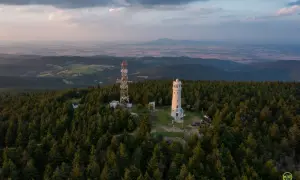 Wieża widokowa i maszt telekomunikacyjny na szczycie góry, otoczone lasem. Widok na rozległą dolinę, jakby wielka sowa ile się wchodziło na szczyt.