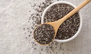 Semi di chia in una ciotola e cucchiaio di legno, un aiuto naturale per sgonfiare la pancia.