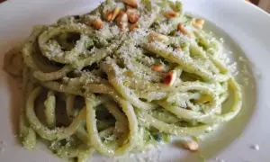 En tallrik med krämig pasta pesto, toppad med pinjenötter och riven parmesan. En härlig italiensk klassiker.