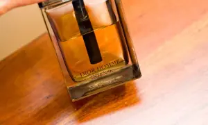 Elegancka butelka Dior Homme Intense z bursztynowym płynem na drewnianym blacie.