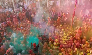 Tłum ludzi w kolorowych strojach, obsypany proszkami podczas święta Holi w Indiach.