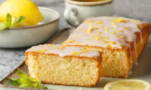 Pyszna babka cytrynowa z lukrem i skórką cytrynową, udekorowana miętą i plasterkiem cytryny. Idealna na podwieczorek.