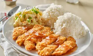 Chrupiąca pierś z kurczaka w panko polana sosem, podana z ryżem i sałatką makaronową.