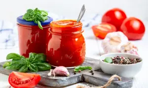 Hausgemachte Tomatensoße für Pizza, mit frischem Basilikum, Knoblauch und Pfefferkörnern.