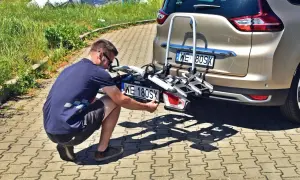 Mężczyzna montuje dodatkową tablicę rejestracyjną na bagażniku rowerowym.