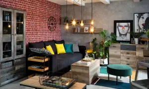 Męski pokój inspiracje: loftowy salon z ceglaną ścianą, czarną kanapą, drewnianymi meblami i industrialnymi lampami.