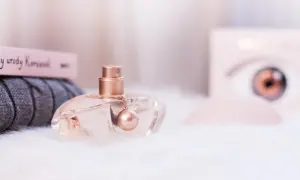 Eleganckie perfumy Kenzo World w szklanym flakonie z złotym detalem, otoczone miękkim futerkiem i książką o urodzie.