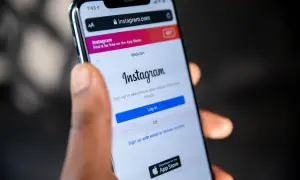 Dłoń trzyma smartfon z ekranem logowania Instagram. Dowiedz się, jak odzyskać skradzione konto na Instagramie, gdy widzisz ten ekran.