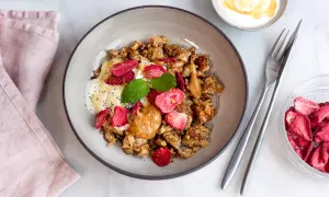 En skål med granola, yoghurt, jordnötssmör, torkade jordgubbar och mynta. En perfekt nyttig frukost för en bra start på dagen.