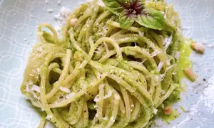 Ein Teller mit köstlichen Pesto Nudeln, garniert mit frischem Basilikum und Pinienkernen.