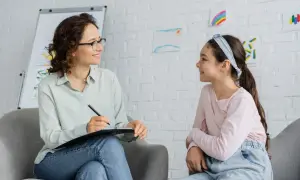 Psycholog rozmawia z dziewczynką, która ma zespół Aspergera. Czy asperger to autyzm? Dzieci rysują na ścianie.