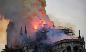 Notre Dame pożar: płomienie trawią dach katedry, unoszą się kłęby dymu. Widoczne rusztowania i zniszczona konstrukcja.