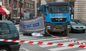 Scène d'accident avec camion bleu, voiture verte et ruban de sécurité. Un autocollant angle mort Europe est visible sur le camion.