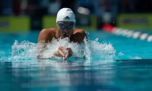Swimmer executing perfect breaststroke technique, arms pulling water, creating a splash.