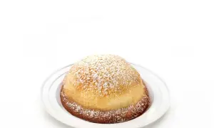 Sfogliatella frolla, un dolce napoletano dalla forma a conchiglia, cosparso di zucchero a velo su un piatto bianco.