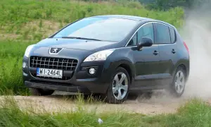 Ciemnoszary Peugeot 3008 2010 na drodze gruntowej, wzbijający tumany kurzu.