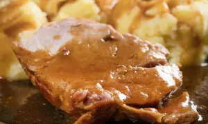 Mięciutka karkówka w sosie, podana z purée ziemniaczanym. Danie wygląda apetycznie i sycąco.