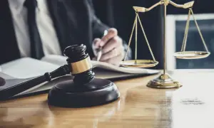 Sądowy młotek i waga sprawiedliwości na biurku. Prawnik pisze, zastanawiając się, po ilu latach przedawnia się prawo do spadku.