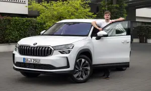 En ung man lutar sig mot en vit Skoda Kodiaq med öppen dörr. Bilen är redo för ett skoda kodiaq test.