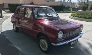 En röd Simca 1100 står parkerad på en solig uppfart.