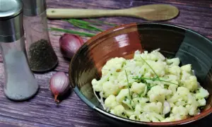 Leckerer gekochter blumenkohlsalat rezepte mit Schalotten und Schnittlauch. Daneben Salz- und Pfefferstreuer.