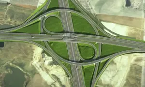 Widok z lotu ptaka na skomplikowany węzeł drogowy, część obwodnicy metropolitalnej Trójmiasta, z zielonymi terenami i wijącymi się estakadami.