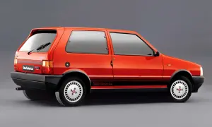 Pomarańczowy Fiat Uno Turbo Le. z czarnymi pasami na boku i felgami w stylu retro.