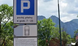 Znaki parkingowe w Zakopanem, informujące o płatnym postoju i cenniku. W tle góry i drzewa, idealne na trasę do skoczni.